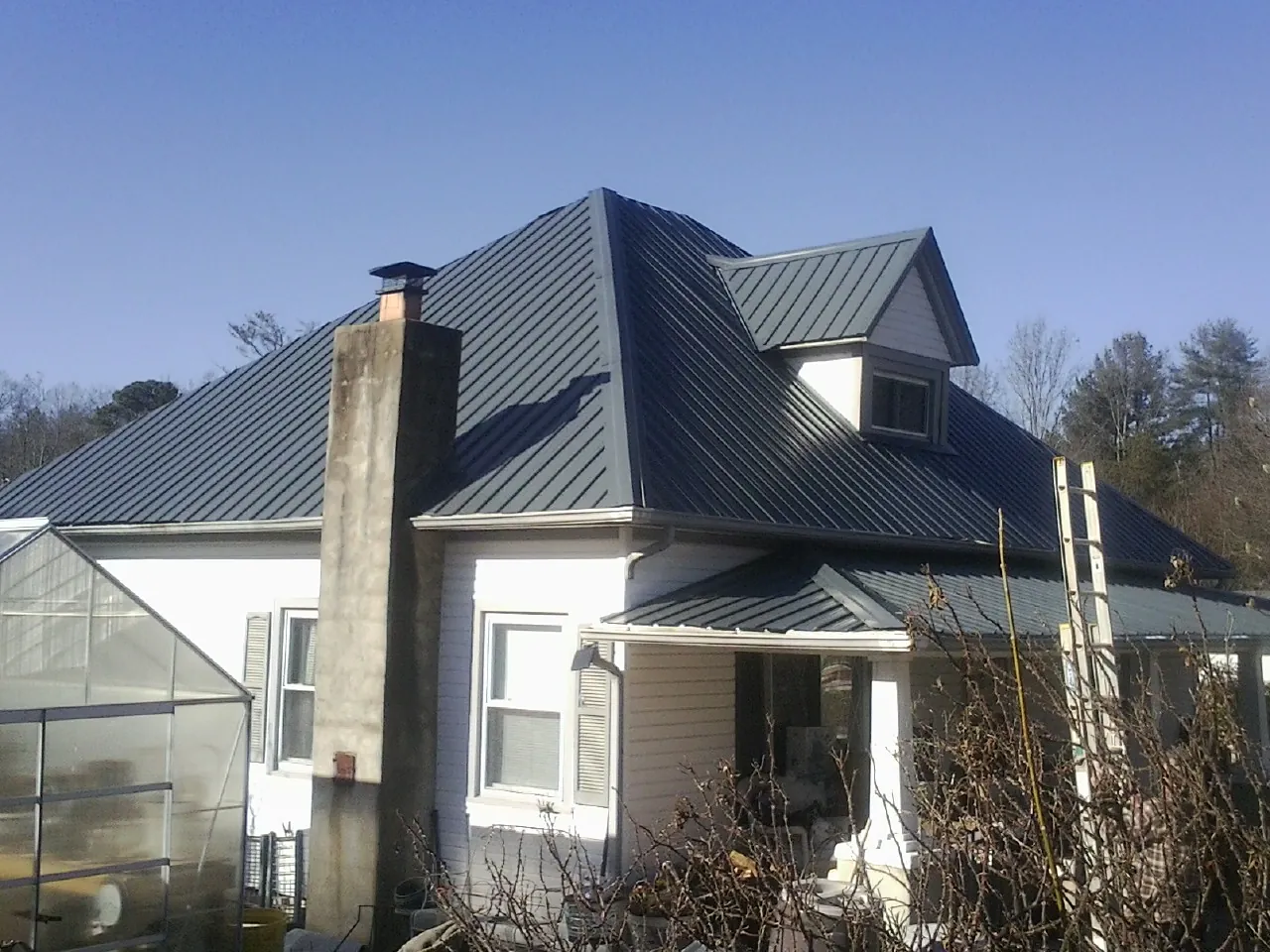 Dark blue standing seam metal roof on a white farmhouse with dormer — Slate & Tile Roof Repair by Roofing Brothers in Corvallis