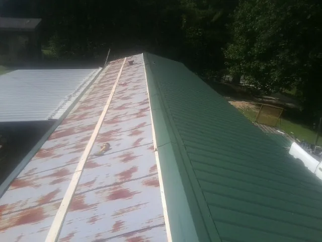 Old rusted panels beside newly installed green metal roofing — Wind Damage Roof Repair by Roofing Brothers in Corvallis