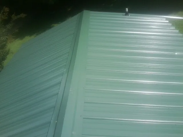 New green metal panels meeting at the ridge of a roof — Flat Roof Repair work by our crew in Corvallis