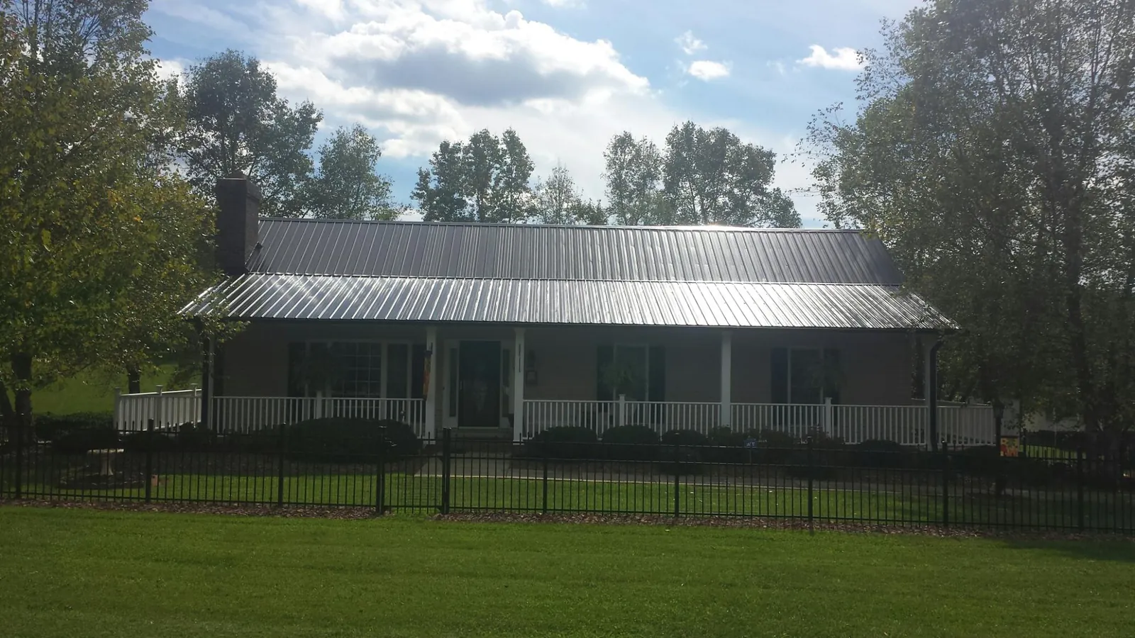 Gray metal roof on a brick ranch with a full width front porch — Gutter Guard Installation work by our crew in Corvallis