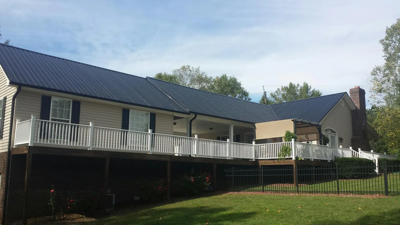 Black metal roof above a long white railed deck on a hillside home in Corvallis