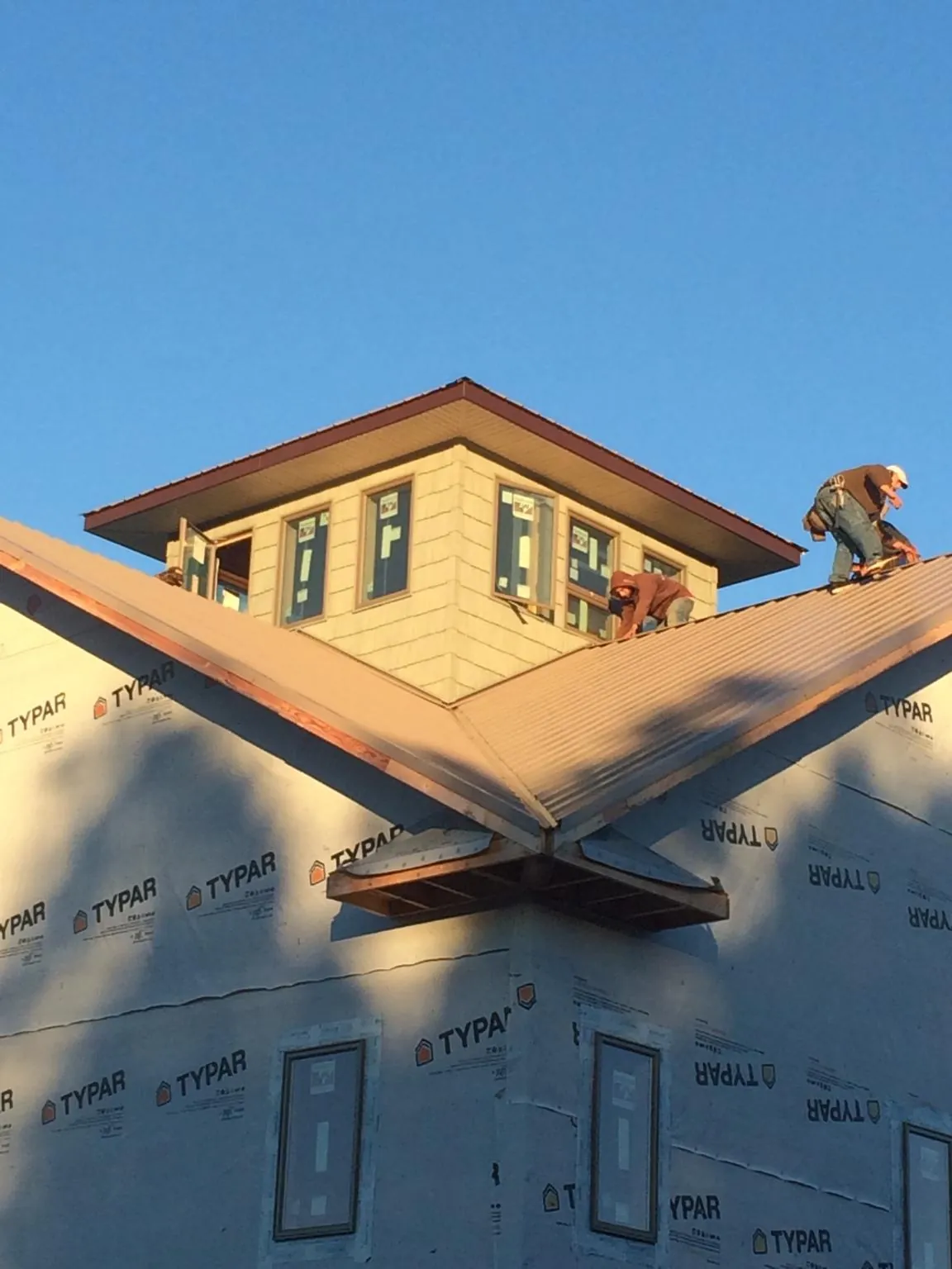 Roofers working around a rooftop cupola on a new metal roof at sunset — Roof Waterproofing in Corvallis by Roofing Brothers